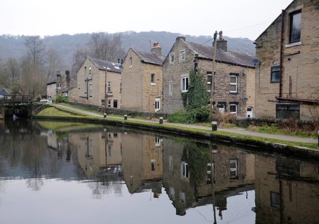 Houses alongside the rochdale canal in hebden bridge with reflections in the water and lock gates