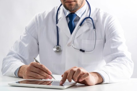 Close up of male doctor hands using tablet computer. Physician in white medical uniform with