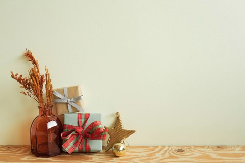 Gift boxes, vase of dry flower, christmas ornament on wooden table. ivory wall background. winter