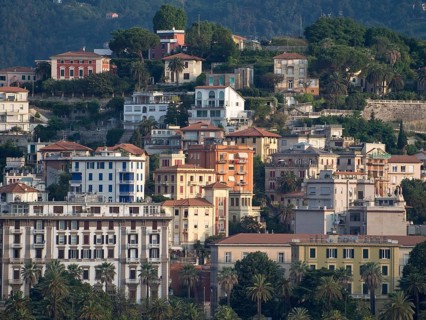 View of colourful houses nestled on a hill surrounded by lush vegetation, La Spezia, Italy
