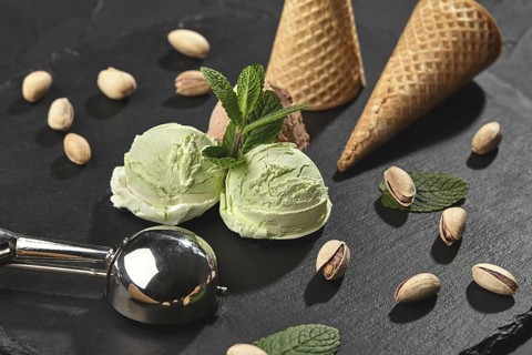Frozen chocolate and pistachio ice cream decorated with mint, waffle cones with scattered