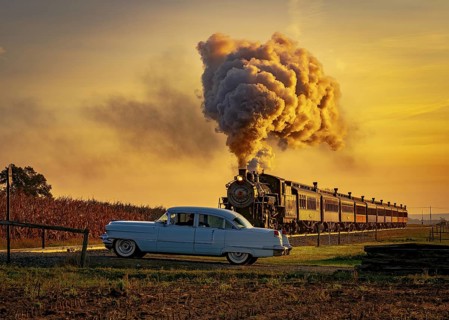A View of an Antique Steam Passenger Train Approaching at Sunrise With a Full Head of Steam and