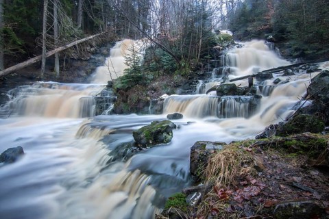 Landscape shot of a large waterfall in a spruce and birch forest and in nature. Autumn landscape