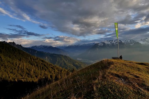 Sitting woman enjoying a dreamlike evening mood in the mountains, view to the Rätikon, flag of the