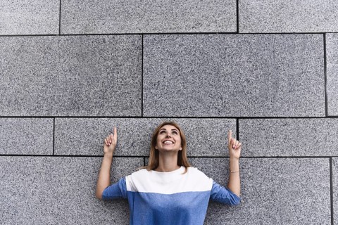 Cheerful girl at the street, show a big sale, or nice offer. Advertise concept. People, travel and
