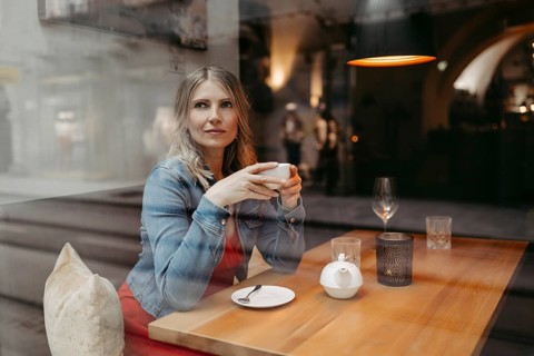 Blonde, attractive woman, 40+, sitting in a coffee house by the window