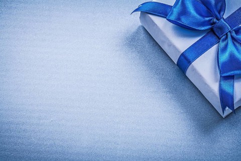 Present box with bow on blue background copyspace holidays concept