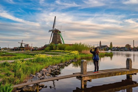 Dutch Windmill at Zaanse Schans Village with woman tourist, Amsterdam Netherlands