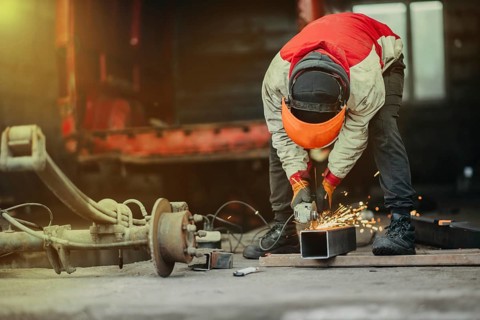 A worker cutting metal with a grinder creating sparks in a workshop