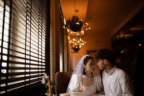Bride and groom share an intimate look in a romantic cafe setting