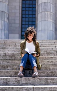 Vertical shot of thoughtful woman sketching on the steps of her college