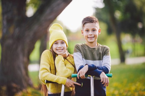 Caucasian children twins boy and girl schoolchildren age pose together in sunny weather in autumn