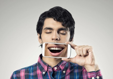 Young man holding smartphone with smile on screen