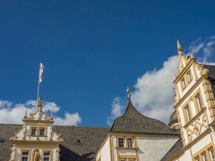 Historic castle with yellow and white façade and towers in front of a blue sky with clouds, Neuhaus