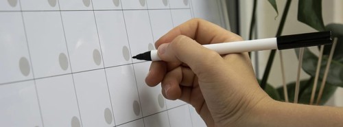 Female hand writing with marker on Monthly PLANNER. Magnetic board with the days of the month.