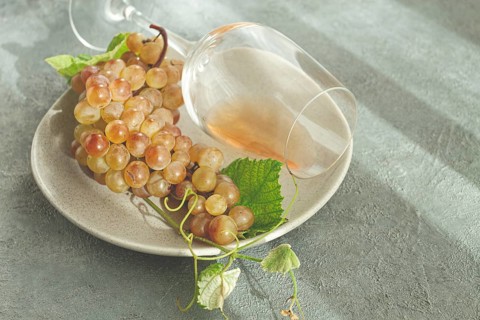 A branch of white grapes, on a gray plate, with a glass of white wine, top view, natural light,