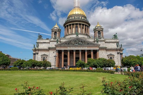 Large cathedral with golden dome, surrounded by greenery and covered by a partly cloudy sky, saint