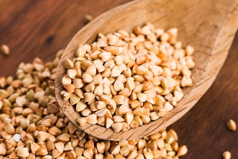 Buckwheat with a spoon on a wooden boards background