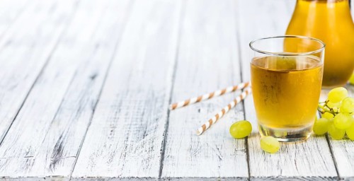 Healthy Grape Juice on a wooden table as detailed close-up shot (selective focus)