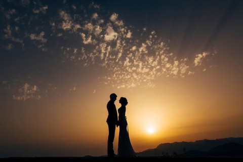 Silhouette of the newlyweds against the sky at sunset. Wedding in Montenegro. Silhouette of a
