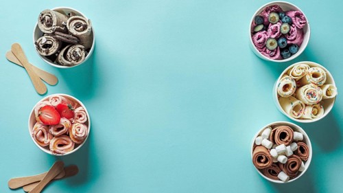 Rolled ice creams in cone cups on blue background. Different iced rolls top view or flat lay. Thai