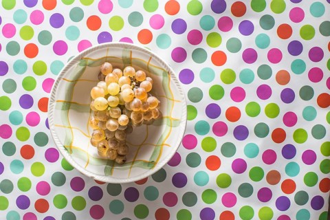 Plate with grape on colorful background