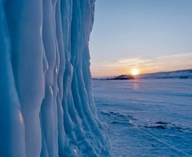 Icicles hang from the rocks on Lake Baikal at frosty winter sunset