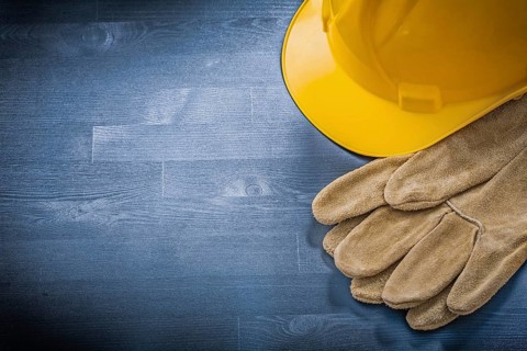Protective gloves building helmet on wooden board construction concept