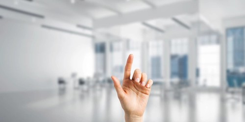 Close of woman hand touching screen with finger and office at background