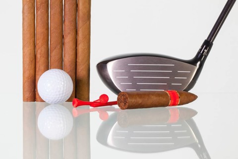 Golf driver and different cigars on a glass table