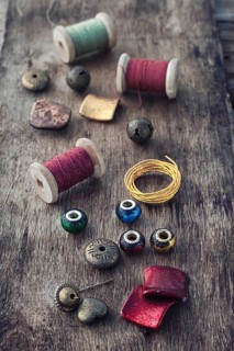 The spool of thread, beads and wire for needlework on wooden background