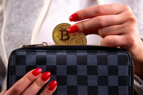 Virtual cryptocurrency money Bitcoin golden coins in the left hand of a woman with red nail polish