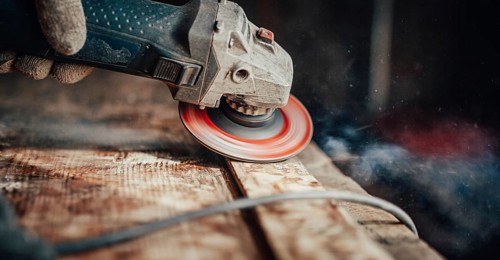 A grinder on wood creating dust and spirals, focused and dynamic