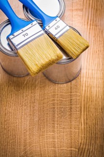 Vertical view organized copyspace two paint brushes on three cans and wooden board