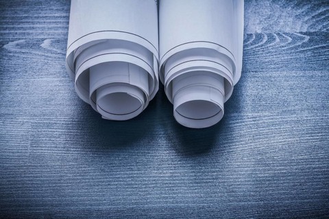 White rolled up blueprints on blue painted board