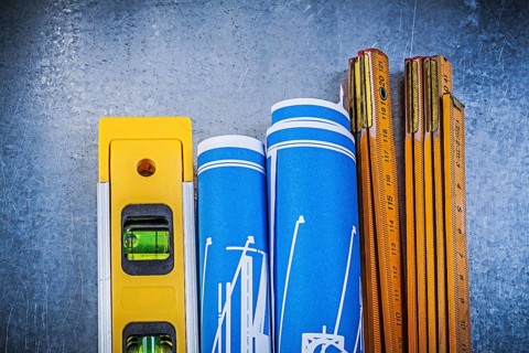 Wooden meter blue construction drawings level on metallic background