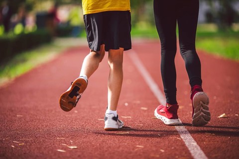 Close-up of the legs in trainers of two children on the running track in the stadium, back view.
