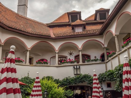 Historic courtyard with arcades, balconies, red and white umbrellas and many plants, Dürnstein,