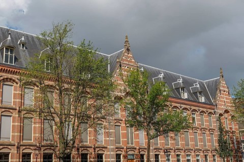 Historic buildings with gables and trees, cloudy sky, Amsterdam, Netherlands