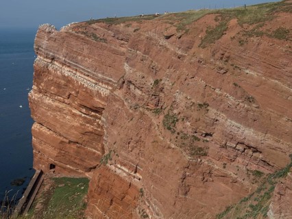 Steep red cliffs with grassy upper ridge on the coast, helgoland, north sea, germany
