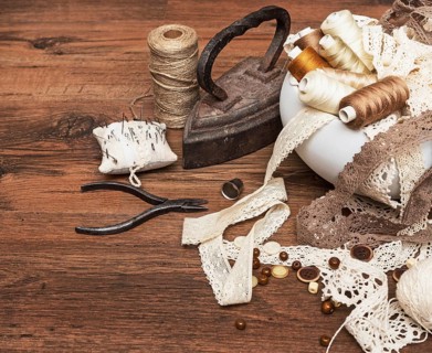Sewing concept. Old flatiron, thread spools, buttons and sewing needles
