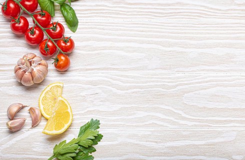 Healthy food ingredients composition with fresh cherry tomatoes, herbs, garlic cloves, lemon wedges