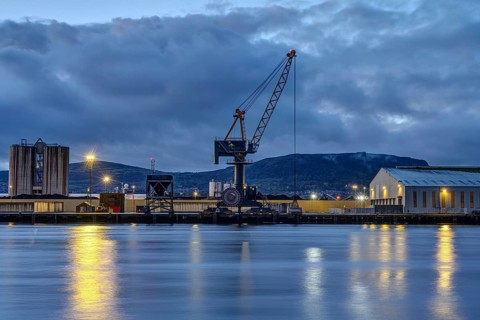 A loading crane and warehouses in Belfast harbour at dusk
