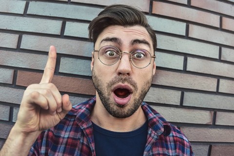 Great idea! Handsome man keeping finger pointed upwards, showing something above his head, making