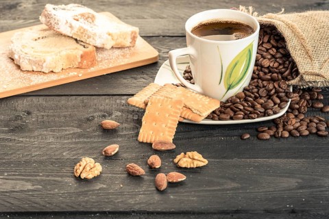 Healthy snack with slices of pound cake, biscuits, almonds, walnuts and a cup of coffee on a plate
