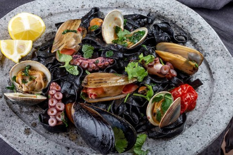 Food, Seafood black fettuccine fehttuchini. Black pasta with squids, octopus clams, mussels on