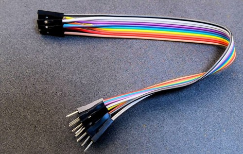 Rainbow jumper wires with pin connectors placed on a blue-toned surface