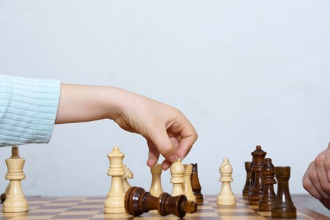 Close-up of a child's hands playing chess with a white background and copy space