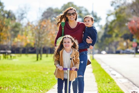 Mother daughter and son family in the park walking with ball and skate scooter
