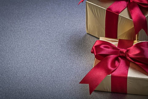 Present boxes in glittery paper on grey background horizontal view holidays concept